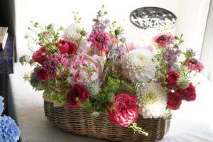 還暦・福岡花屋・フラワーアレンジ　赤系をいれて優しいイメージでご依頼　持ち手付きのかごアレンジはお花が枯れた後も籠を使用できるので人気です